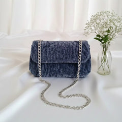 Denim handbag with a chain strap on a white surface