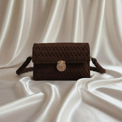 Brown woven handbag with a gold clasp on a white fabric background