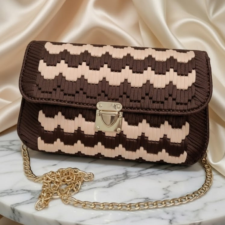 Brown and beige patterned handbag with gold chain on a marble surface