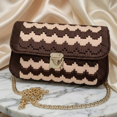 Brown and beige patterned handbag with gold chain on a marble surface