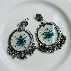 Ornate earrings with blue floral design on a white plate
