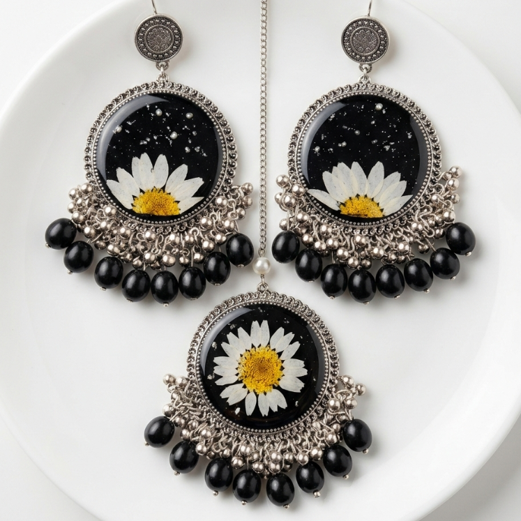 Black and silver earrings with daisy flowers on a white plate
