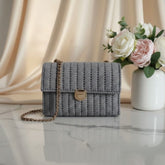 Gray woven handbag with a gold chain.