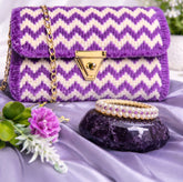 Purple and white chevron patterned handbag with gold accents on a purple fabric background.