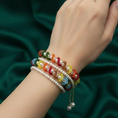 Hand wearing colorful beaded bracelets on a dark green fabric background