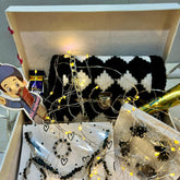 Decorative box with jewelry, fairy lights, and a bottle of champagne on a checkered tablecloth.