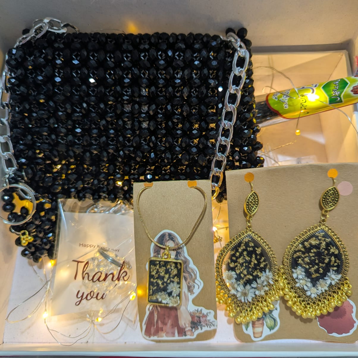 Black beaded handbag with jewelry on a white surface