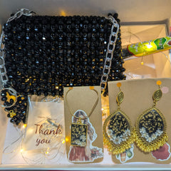 Black beaded handbag with jewelry on a white surface