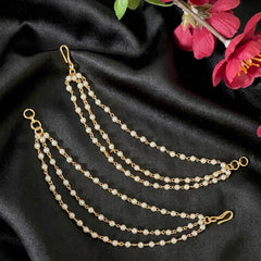 Gold chain with pearls on a black fabric background with pink flowers.