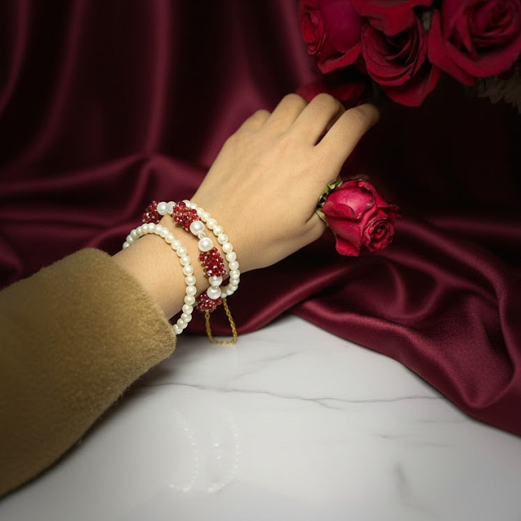 Hand wearing a bracelet with red and gold accents, holding red roses.