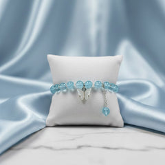 Blue beaded bracelet on a white pillow with a blue satin background