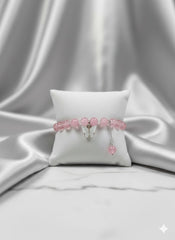 Pink beaded bracelet on a white pillow with a gray fabric background