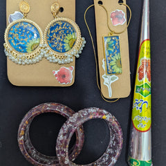 Pair of floral earrings on Inci Aura cards with two bangles and a cone on a black background