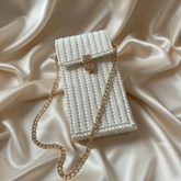 White woven handbag with a gold chain on a beige fabric background