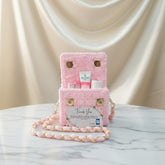 Pink plush bag with gold chain on a marble surface