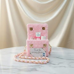 Pink plush bag with gold chain on a marble surface