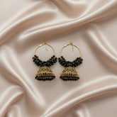 Pair of gold and black beaded earrings on a satin surface