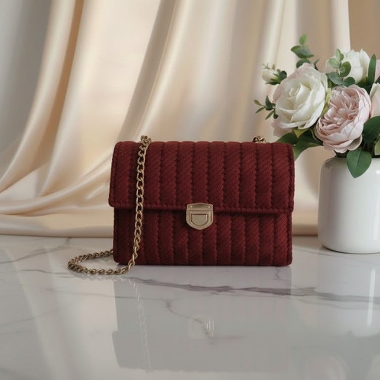 Red textured handbag with a gold chain.