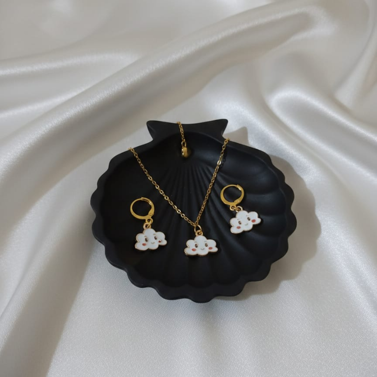 Jewelry set with necklace and earrings on a black dish against a white fabric background
