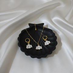 Jewelry set with necklace and earrings on a black dish against a white fabric background