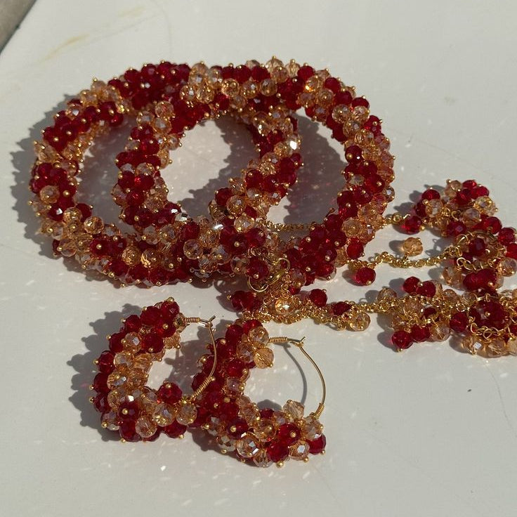 Set of red and gold beaded jewelry including gajra, and earrings on a white surface.