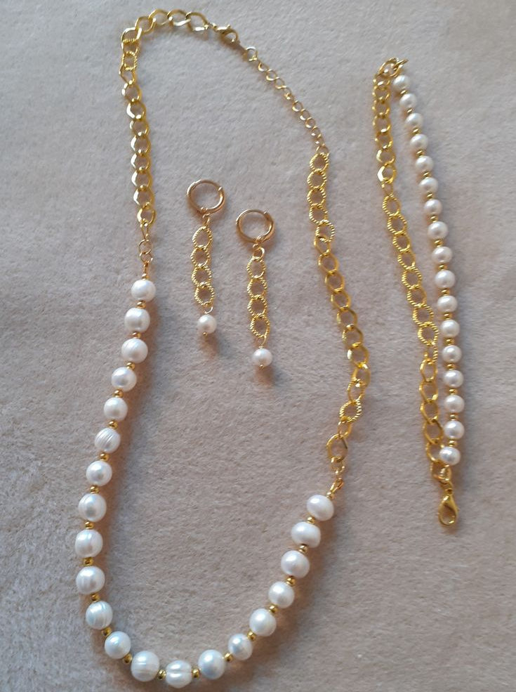 Pearl necklace and earrings on a light gray surface
