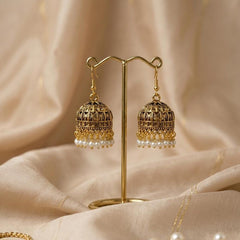 Gold earrings with pearl drops on a beige fabric background