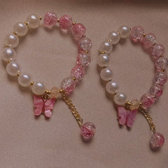 Two beaded bracelets with pink butterfly charms on a beige background