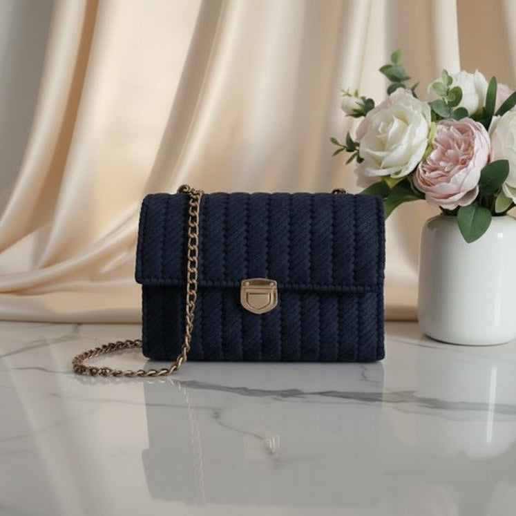 Navy blue knitted handbag with a gold chain.