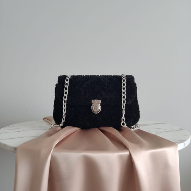 Black textured handbag with a chain strap.