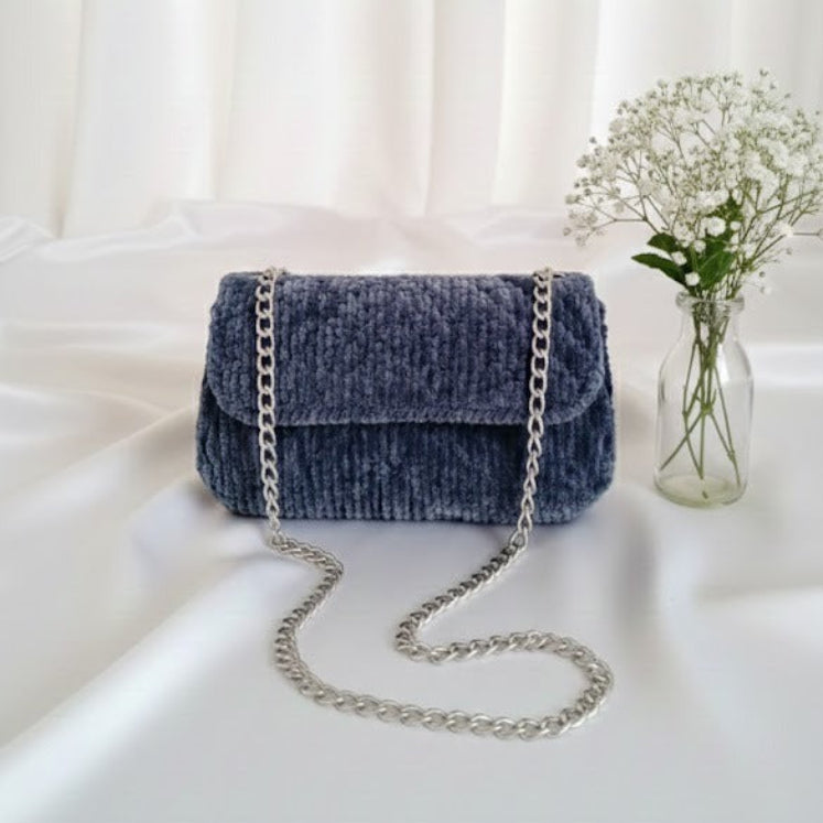 Denim handbag with a chain strap on a white surface 