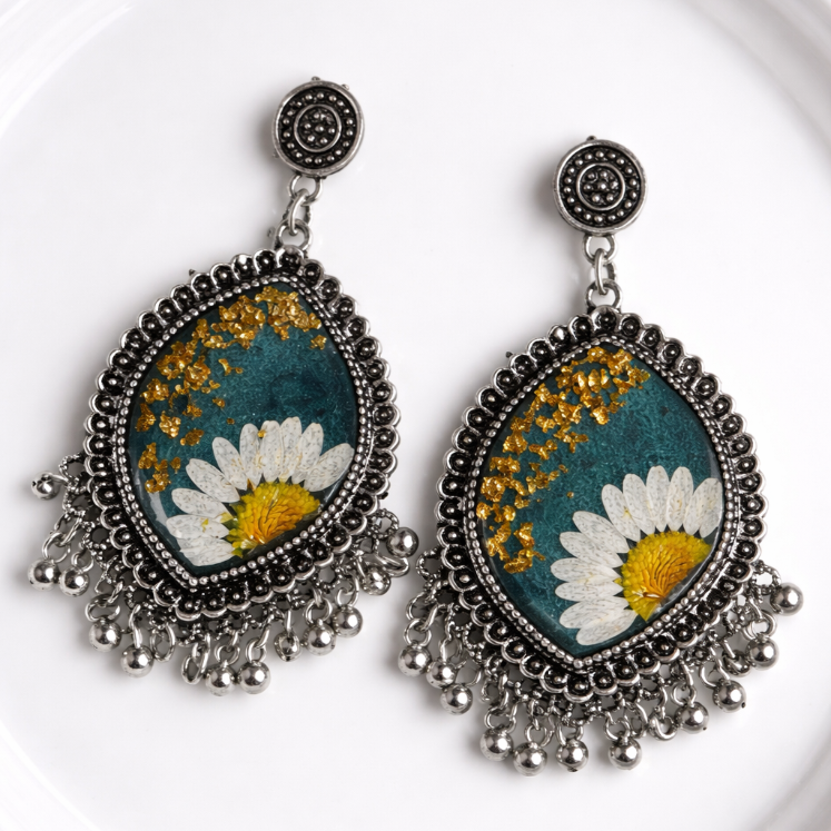Pair of floral earrings with teal background on a white plate