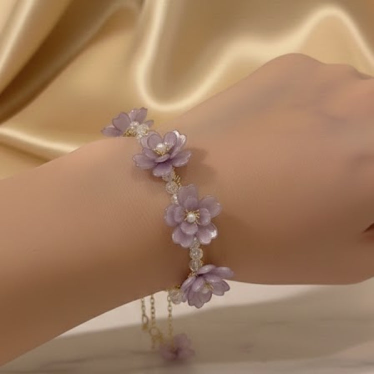 Hand wearing a delicate purple floral bracelet 