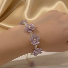 Hand wearing a delicate purple floral bracelet 