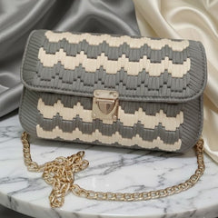 Gray and white patterned handbag with gold chain on a marble surface
