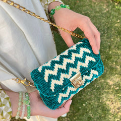 Teal and white zigzag patterned handbag held by a person with green grass in the background