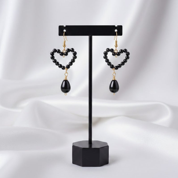 Heart-shaped earrings on a black stand against a white background