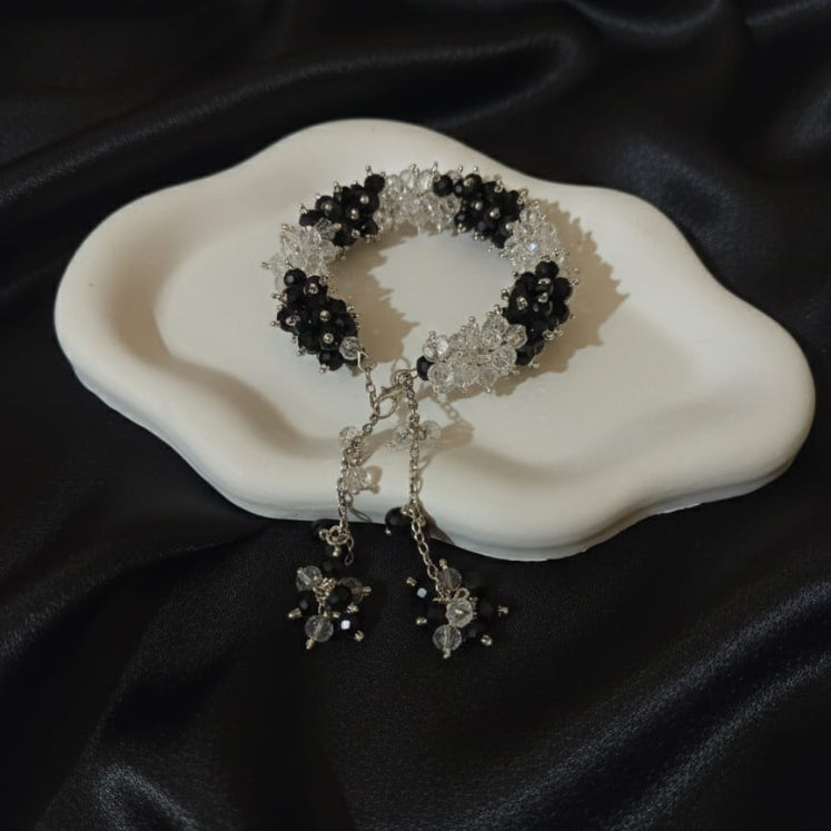 Black and white beaded bracelet on a white dish with black fabric background