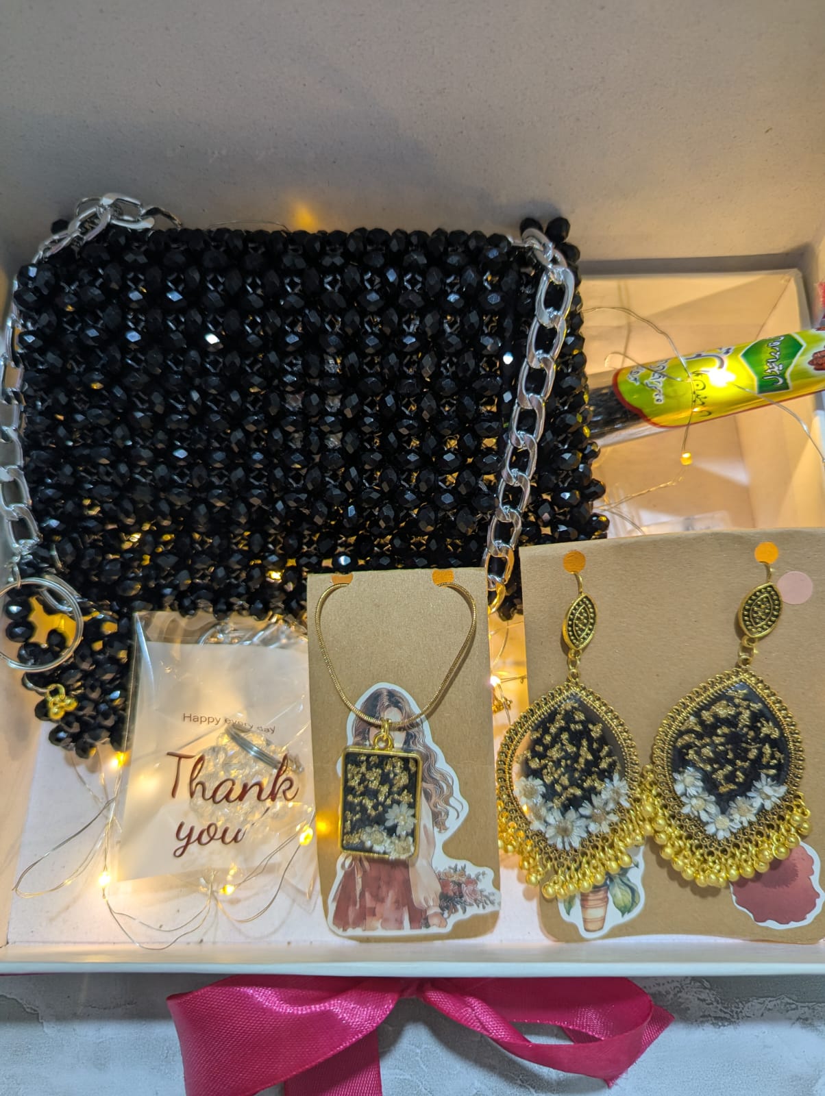 Black beaded handbag with jewelry on a white surface