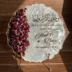 Decorative plate with engraved text and floral design on a wooden surface