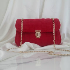 Red handbag with a gold chain on a white fabric background