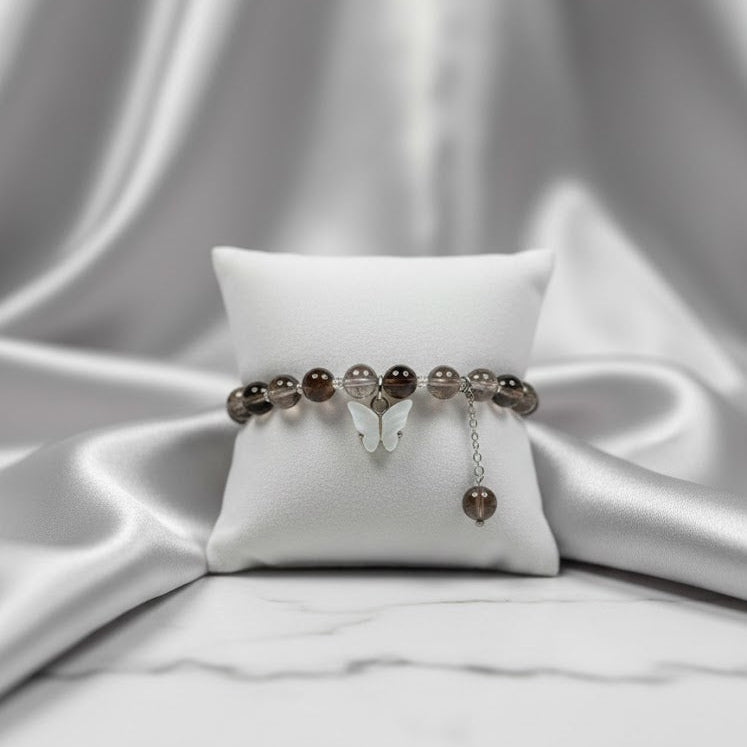 Bracelet with brown beads on a white pillow against a white fabric background