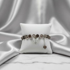 Bracelet with brown beads on a white pillow against a white fabric background