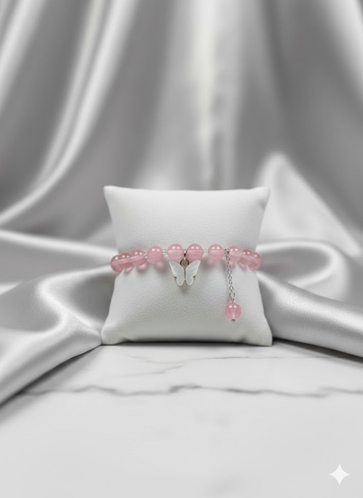Pink beaded bracelet on a white pillow with a gray fabric background