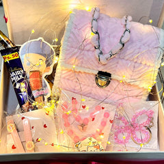 Gift box with pink backpack, stationery items, and chocolate on a gray surface.