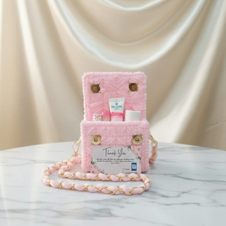 Pink plush bag with gold chain on a marble surface 