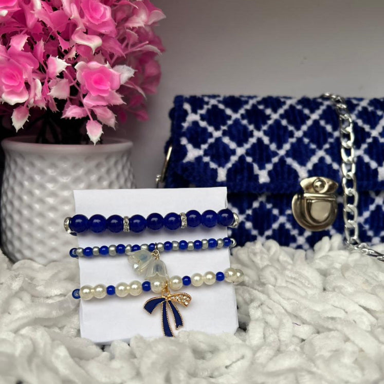 Set of blue and white jewelry on a card with a blue patterned handbag in the background.