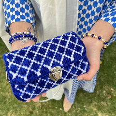 Person holding a blue patterned bag and bracelet