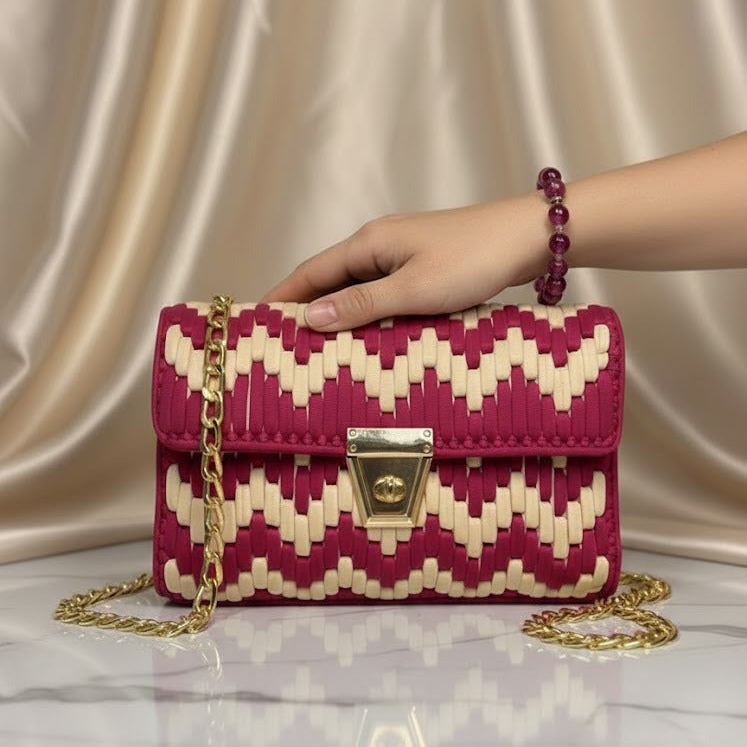 Hand holding a red and skin patterned handbag with a gold chain 