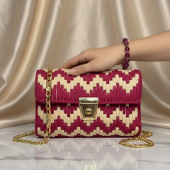 Hand holding a red and skin patterned handbag with a gold chain 